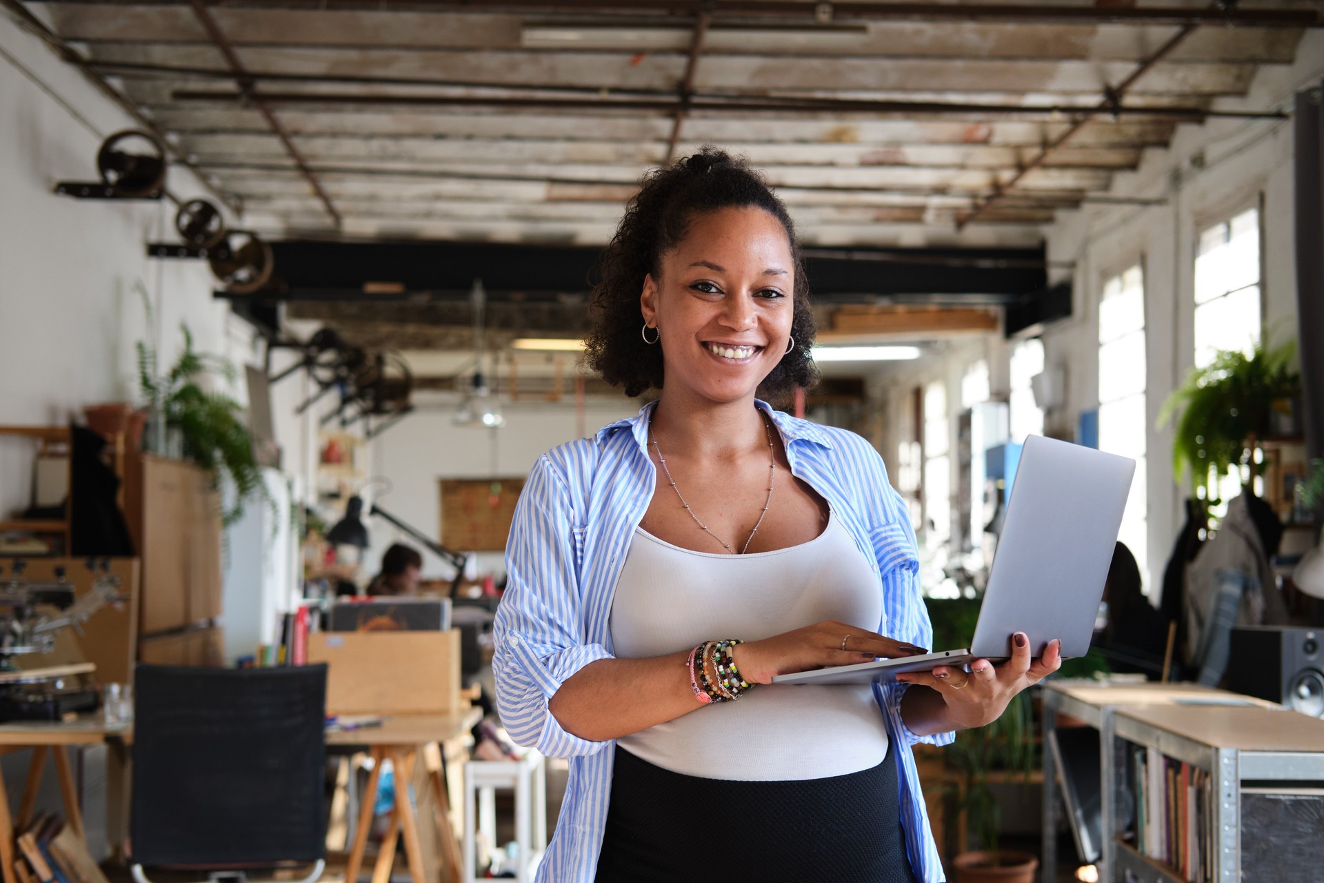 waist shot of an African descendent pregnant woman taking a break from business looking at the camera proud and smiling in a modern co-working